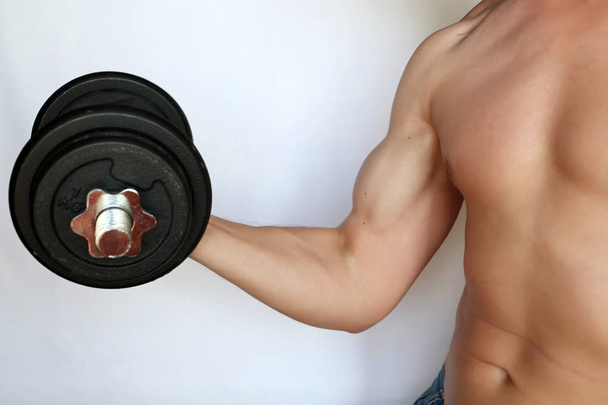 Muscular guy training with dumbbell, exercises for biceps. Concept of weightlifting in the gym, bodybuilding - Foto, Imagen