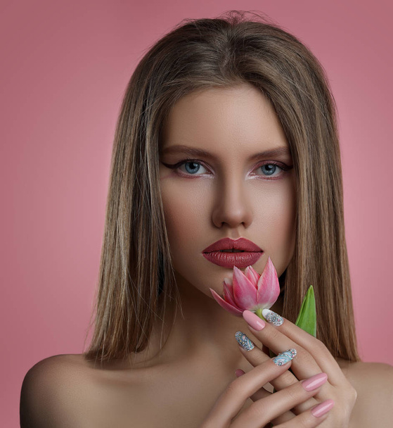 Beauty portrait of young woman with flower . Model girl with professional make-up and Nail art manicure over pink background. - Fotoğraf, Görsel