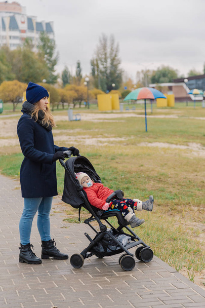 Egy nő sétál a parkban egy babakocsi és egy kisgyerek a tónál. - Fotó, kép