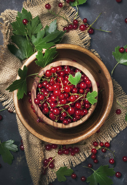 Red currant in wooden bowl on canvas napkin, rustic style, summer food background, top view - Fotó, kép