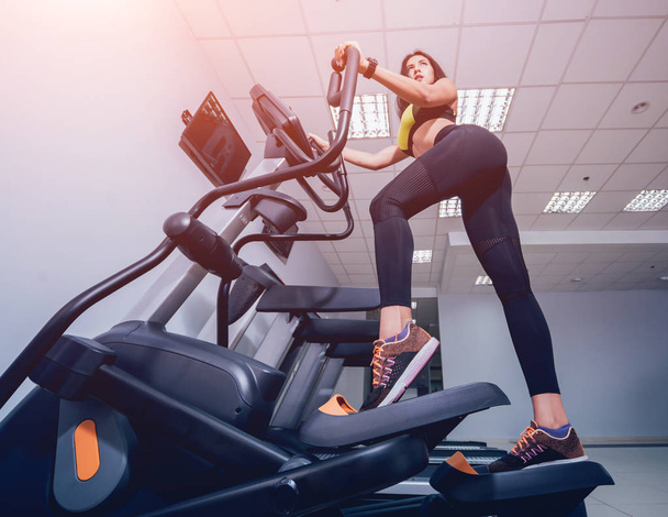 Young woman training on cross trainer at the gym. Peoples in fitness center. Treadmill. Health concept - Foto, immagini