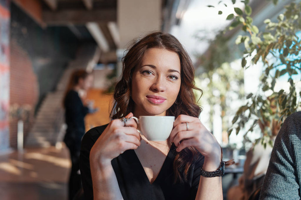 Attractive woman drinking tea at lunch break from white cup and smiling. - Foto, Bild