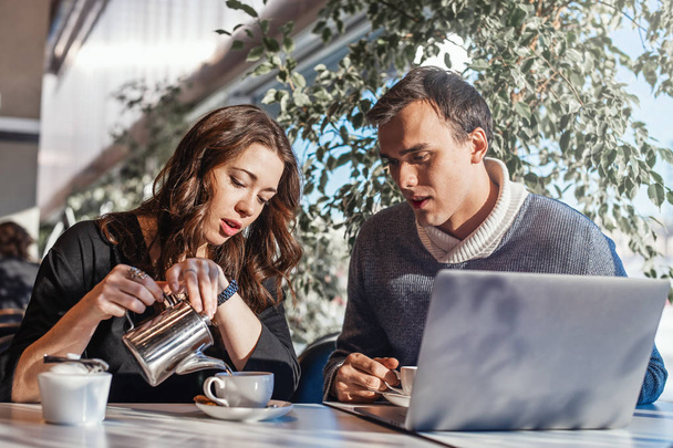 Young man and woman working in front of the laptop and drinking tea. - Фото, изображение