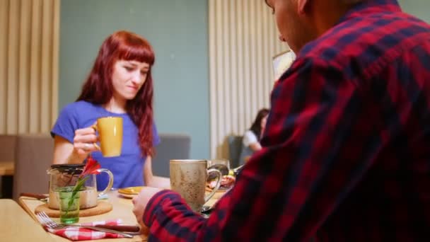 Una pareja sentada a la mesa en un café. Beber té. Un camarero trae el pedido
 - Imágenes, Vídeo