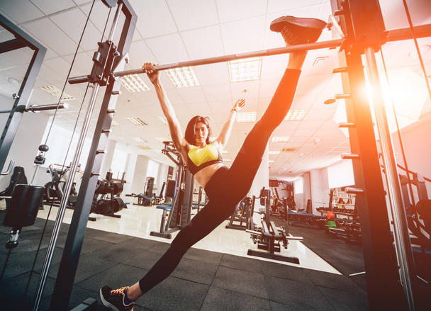 Beautiful athletic young woman making exercise at the gym. Young woman with muscular body. Fitness concept. - 写真・画像