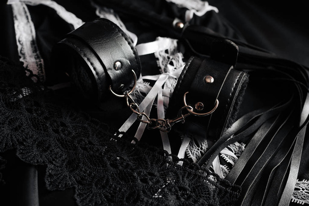 Lederhandschellen und Peitsche für BDSM und Dienstmädchenkostüm für Rollenspiele - Foto, Bild