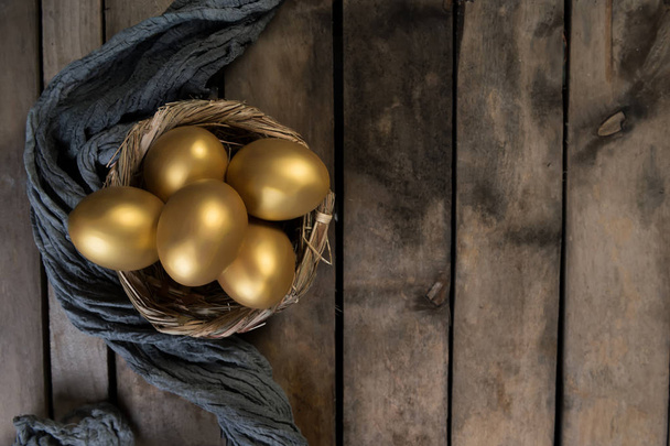 Huevos dorados en nido sobre fondo oscuro de madera vintage
 - Foto, imagen
