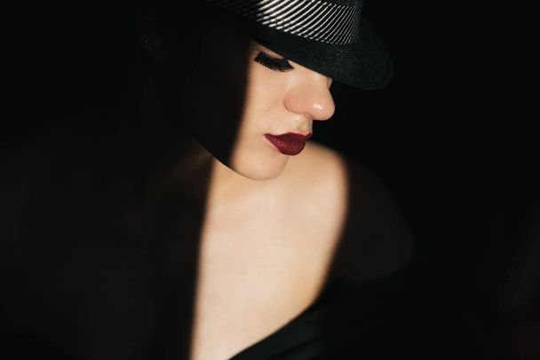 fashion portrait in profile of a young sexy girl in a black hat with red lipstick - Fotoğraf, Görsel