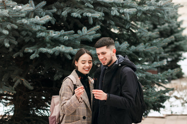 Romântico jovem casal está se divertindo ao ar livre no inverno antes do Natal com luzes de bengala
 - Foto, Imagem