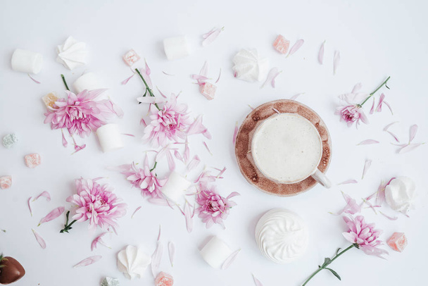 Chocolade snoepjes, Zephyrs, Marshmallow, roze bloemen en koffie. Vlakke lay.  - Foto, afbeelding