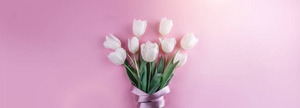 Bouquet of white tulips flowers on pink background. Card for Mothers day, 8 March, Happy Easter. Waiting for spring. Greeting card or wedding invitation. Flat lay, top view - 写真・画像