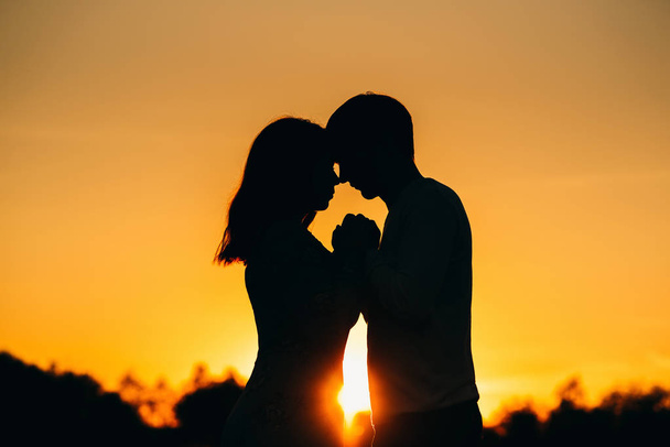 ζευγάρι στην αγάπη κρατά το χέρι σε ένα πορτοκαλί ηλιοβασίλεμα το καλοκαίρι - Φωτογραφία, εικόνα