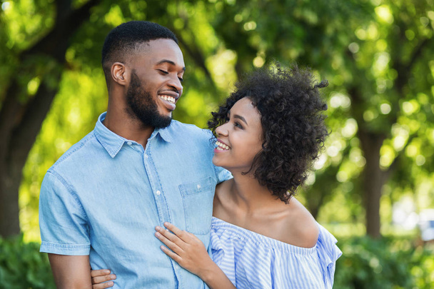 Excited black couple bonding while walking in park - Foto, imagen