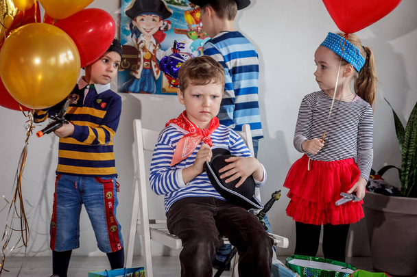 RUSSIA, YAROSLAVL - 17 FEB. 2018: happy group of children at a birthday celebration dressed in the style of pirates with an animator, contests and bubbles play games in a large room with loft style - Photo, Image