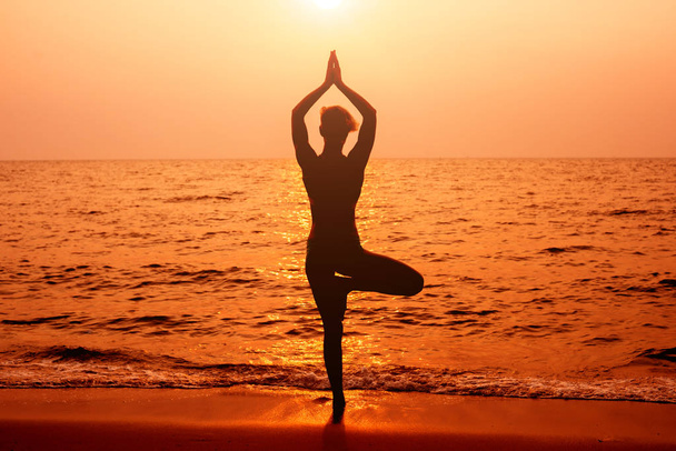 Krásná mladá žena practic jóga na pláži. Ranní cvičení. Dlaně pozadí - Fotografie, Obrázek