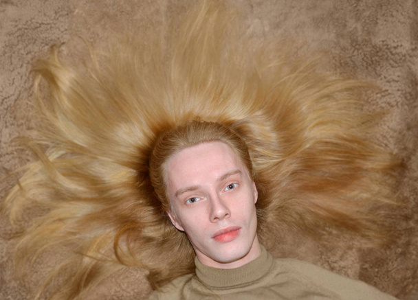 portrait d'un jeune homme aux longs cheveux blonds bien soignés étalés autour de sa tête
 - Photo, image