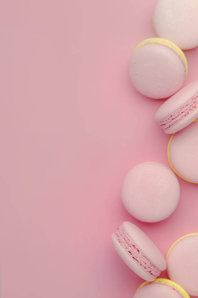 Pink yellow macaroons on soft pink background table, place for text, minimalism style, top view - Fotó, kép