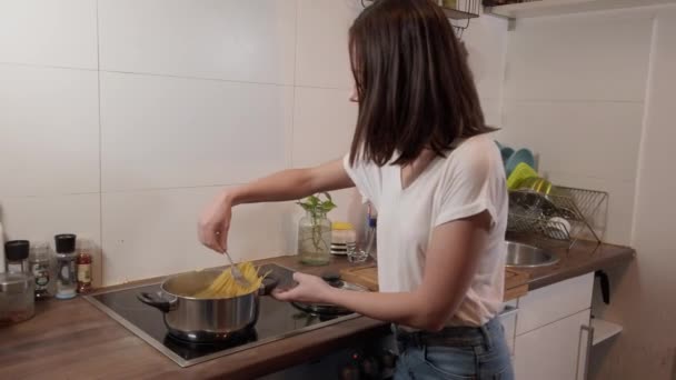 Young woman in the kitchen cooks spaghetti - Filmati, video