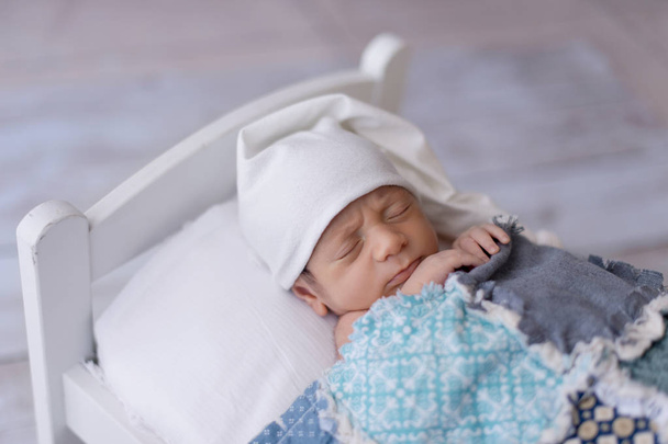 Neugeborener Junge schläft auf winzigem Bett - Foto, Bild