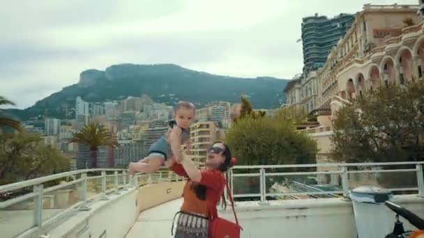 Azjatycka matki i dziecka jako turyści, grając w Monte-Carlo z zabytkowym budynku w tle - Materiał filmowy, wideo