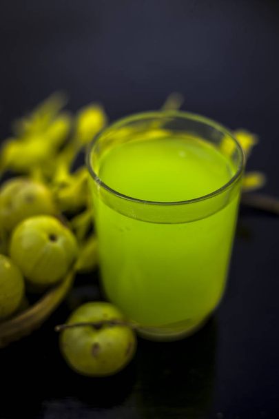Extracted juice of amla in transparent glass with raw fruits on table - Zdjęcie, obraz