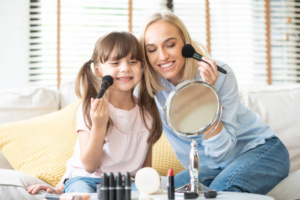 Mother and daughter applying cosmetic. - Foto, afbeelding