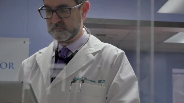 Férfi orvos összpontosít a digitális tabletta a modern orvosi rendelőben - Felvétel, videó