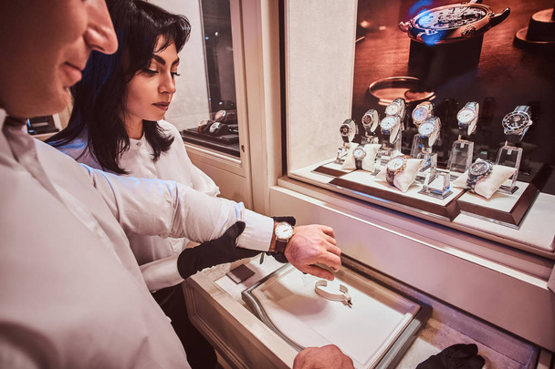 Seller helps the client to try on exclusive mens watches in the luxury jewelry store - Foto, immagini