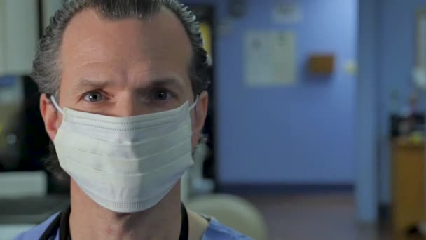 Portrait of a male doctor wearing protective face mask in a clinical setting - 映像、動画