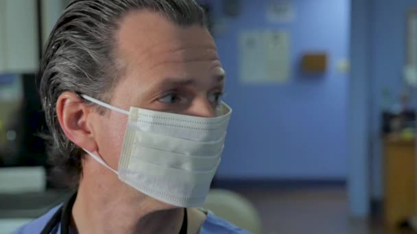 Male doctor or nurse with a face mask turning to look at the camera - Footage, Video