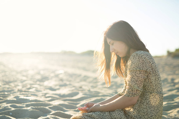 young girl enjoys the sunset on the beach. Beautiful beach, sun rays. Copy space for text - 写真・画像