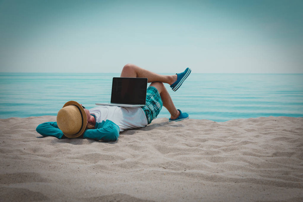 relaxado jovem trabalhando no laptop na praia
 - Foto, Imagem