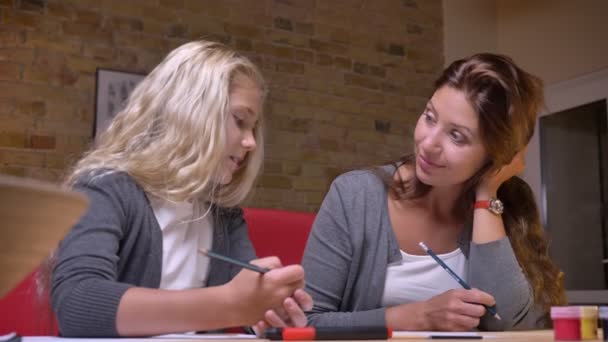 Closeup shoot of young gentle mother and her small pretty daughter drawing spending time together and having a casual talk - Filmagem, Vídeo