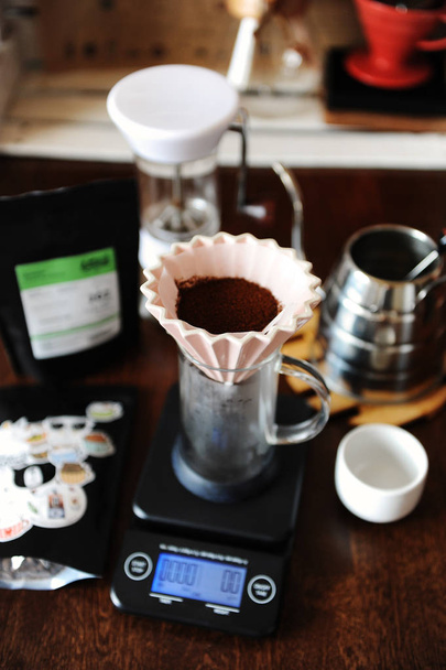 Gemalen koffie in roze keramische origami dripper met papieren filter. Alternatieve koffie brouwen. Handmatige grinder. Zwanenhals waterkoker. Elektronische schaal - Foto, afbeelding