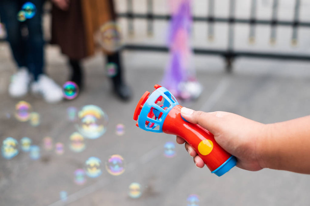 Рука натискає іграшку вентилятора мила бульбашок на повітрі
 - Фото, зображення