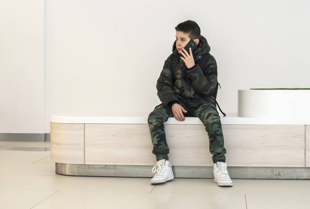 Teenager talking on smartphone in modern commercial center. Tech - Fotó, kép