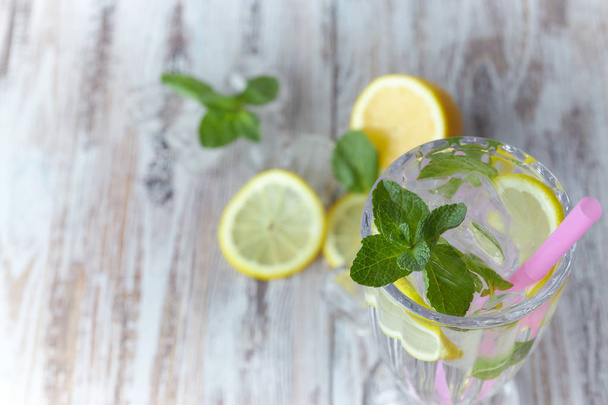 Lemonade with ice and fresh lemon with mint on wooden background. horizontal view. copy space. close-up. refreshing summer drink. - Photo, image