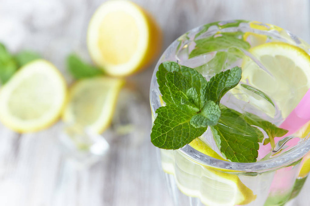 Lemonade with ice and fresh lemon with mint on wooden background. horizontal view. copy space. close-up. refreshing summer drink. - Фото, изображение