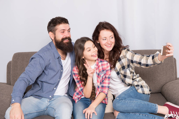 Little girl use smartphone with mother and father. man and woman with little girl. Mother and father do selfie for little girl. Family with little girl. Happy family at home. Collecting memories - Photo, Image