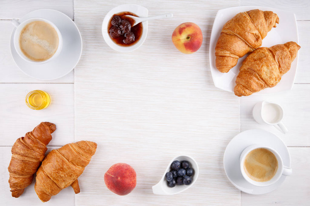 Śniadanie - dwie filiżanki kawy, rogaliki, dżemu, miodu i owoców - Zdjęcie, obraz
