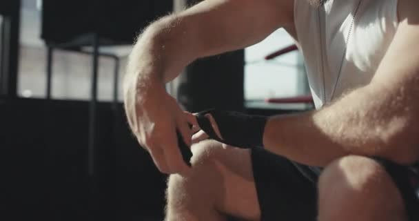 Male boxer wraps his hands with black handwrap before the fight training - Кадры, видео