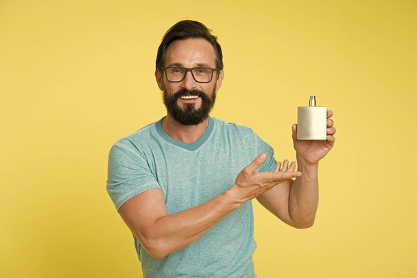 Right perfume fragrance makes you younger. Man bearded handsome smiling face hold bottle perfume defocused. How to pick right fragrance. How to choose best perfume for men according to occasion - Photo, Image