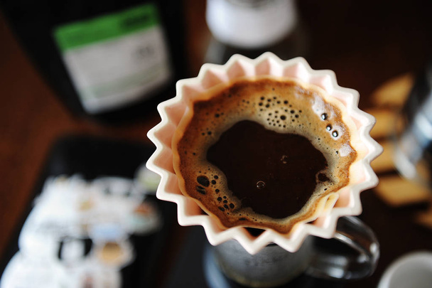 Альтернативна ручна кава для приготування кави в рожевій керамічній крапельниці орігамі з паперовим фільтром. Крупним планом, вид зверху
 - Фото, зображення