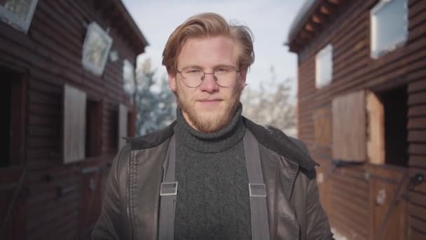 Portrait of a handsome bearded guy with glasses dressed in a warm sweater and jacket. Slow motion. - Filmagem, Vídeo