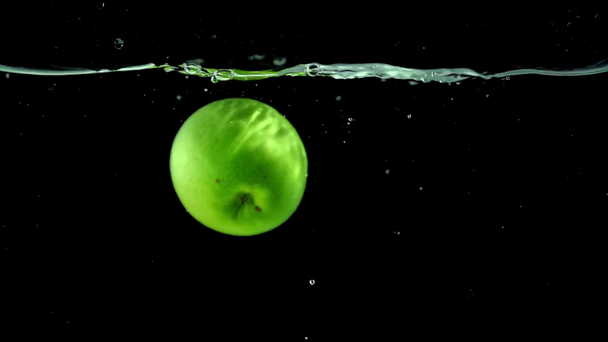 parlak yeşil elma içine düşme temiz su siyah arka plan üzerine  - Video, Çekim