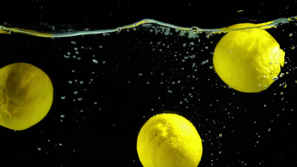 zářivě zelené citrony do čisté vody na černém pozadí  - Záběry, video