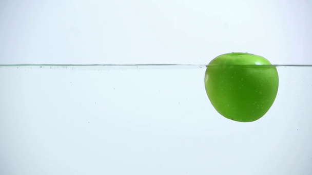 bright green apple turning around in clear water on grey background with backlit - Footage, Video