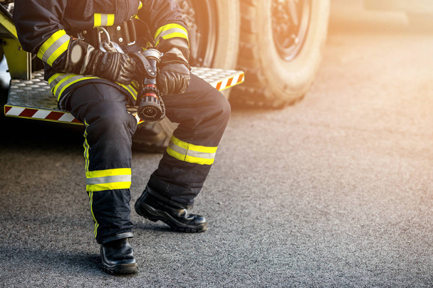 Firefighter Rescue man. Firefighter in uniform and  helmet near fire engine. - 写真・画像