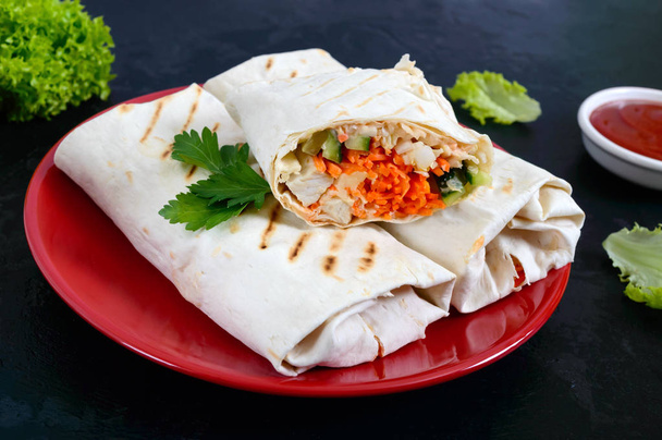 leckeres Shawarma-Sandwich auf schwarzem Hintergrund. Burritos Wraps mit gegrilltem Huhn und Gemüse, Gemüse. fajitas, Fladenbrot. traditionelle Vorspeise aus dem Nahen Osten. Mexikanische Küche - Foto, Bild