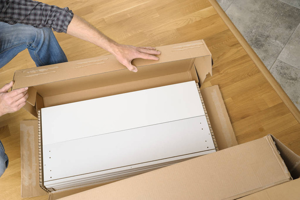 A man is unpacking a cardboard box with furniture. - Foto, immagini